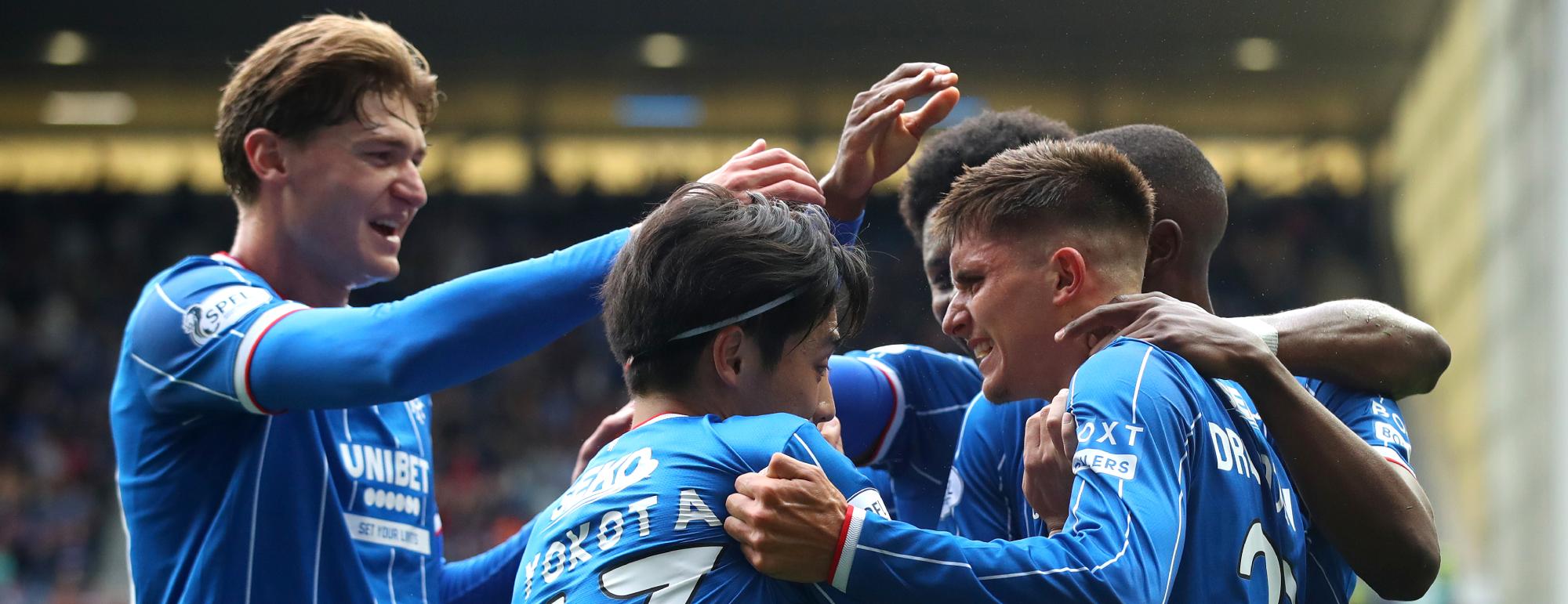 Players in blue celebrate a goal with arms on each others shoulders