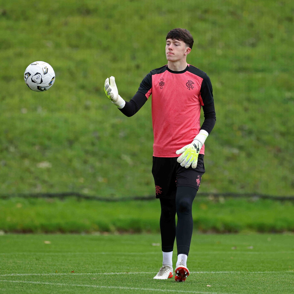 A man in a red and black football shirt catching a ball in the air.