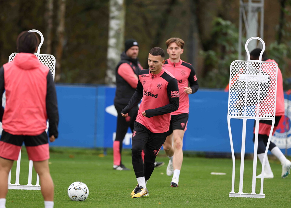 Footballers in pink training shirts run with a soccer ball.