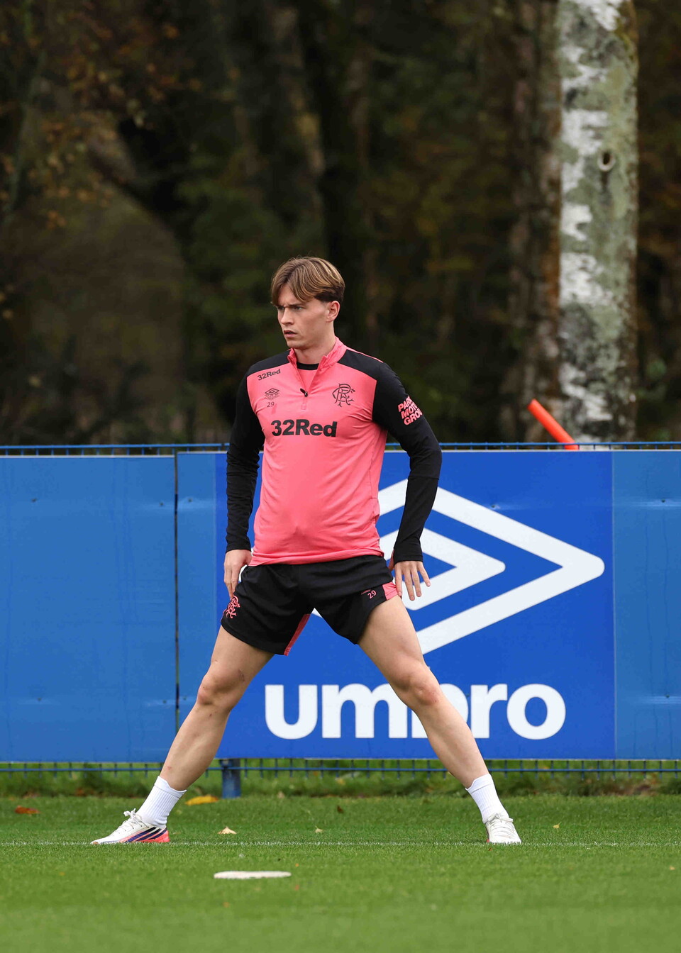 Footballer standing in a pink shirt on a football pitch