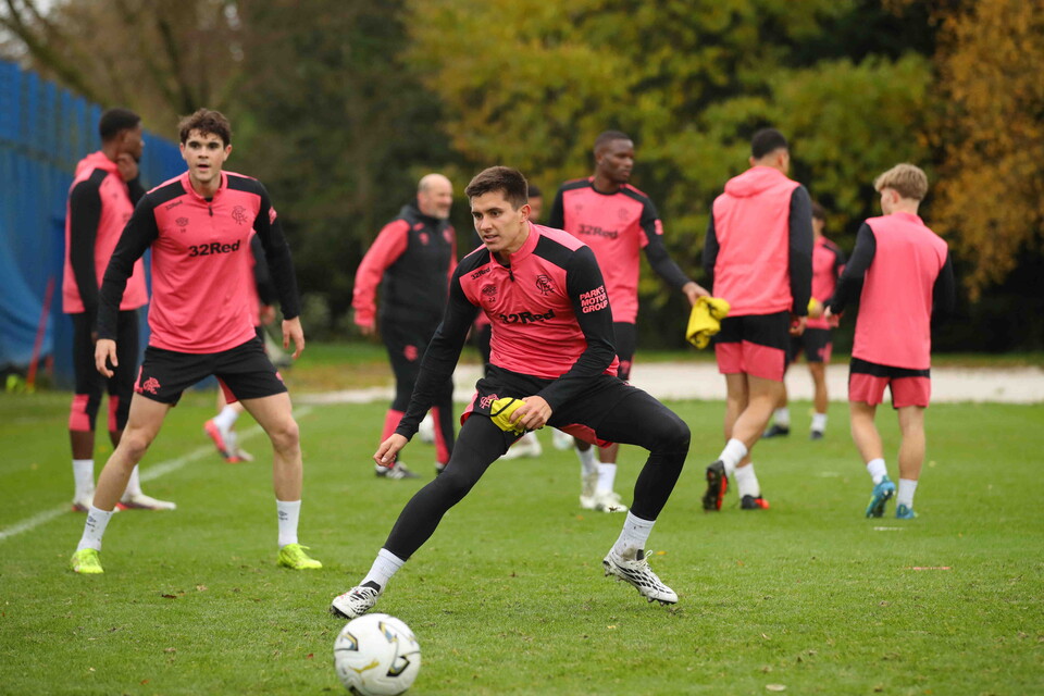 Football players in pink and black kits training on a field, one player kicking a ball