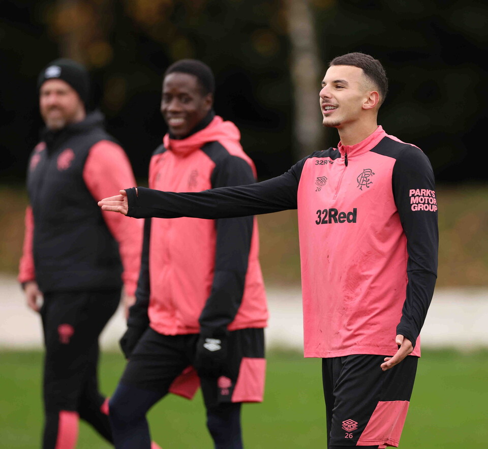 Three football players in training wear, one in black and pink, another in pink and black, and a third in black and pink.