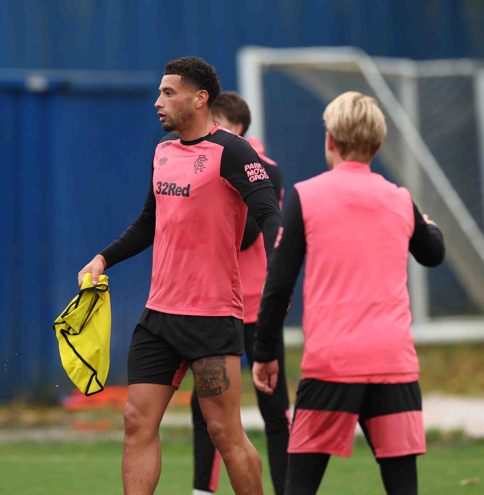 Two players wearing pink and black training kit walking on a pitch