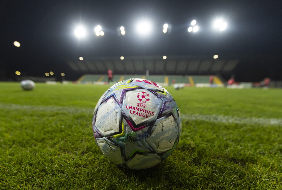 Champions League ball on football pitch with stadium in background