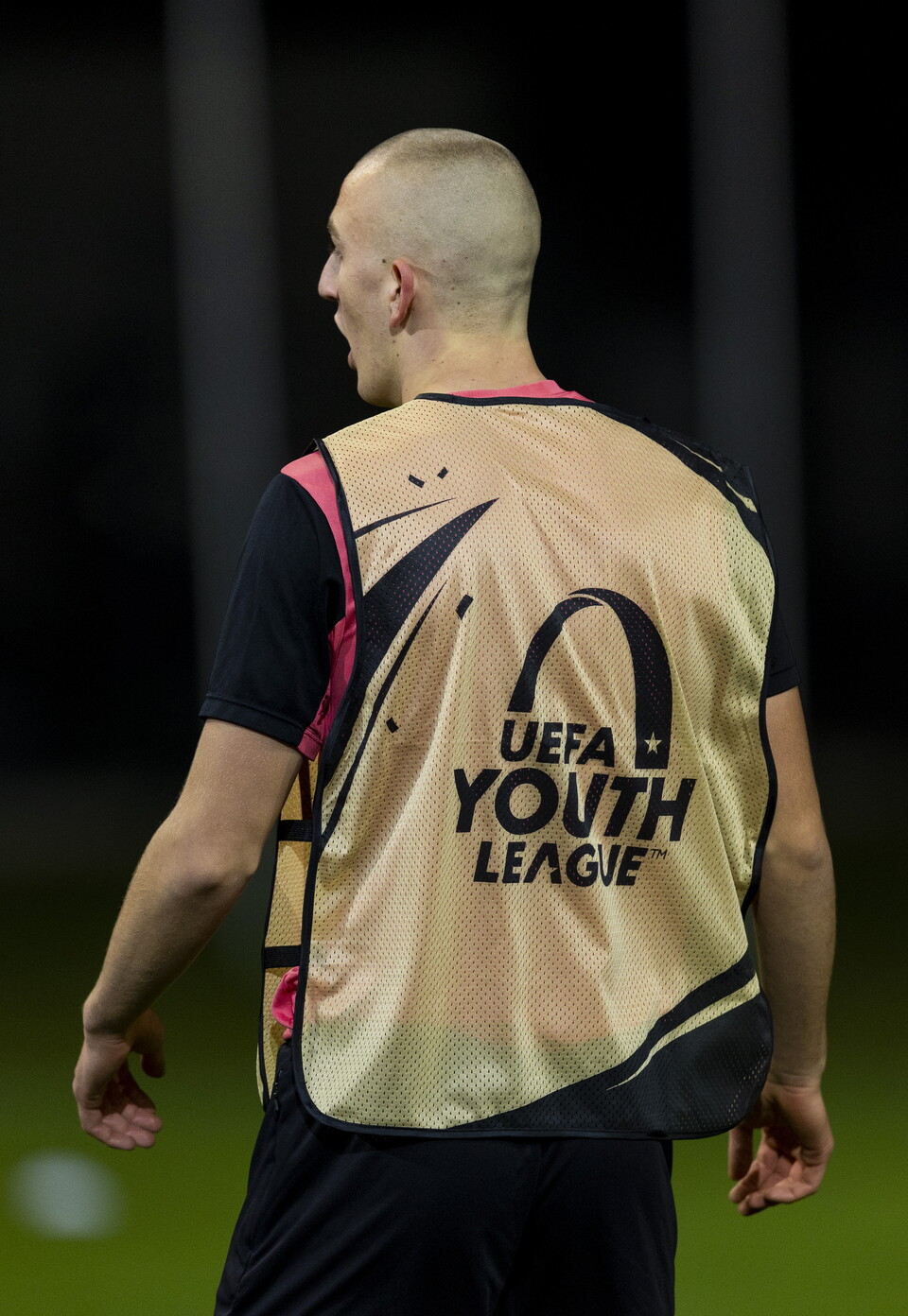 Man wearing a UEFA Youth League vest, back turned.