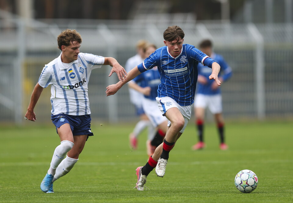 Two players compete for the ball; one in white and blue, the other in blue and white.