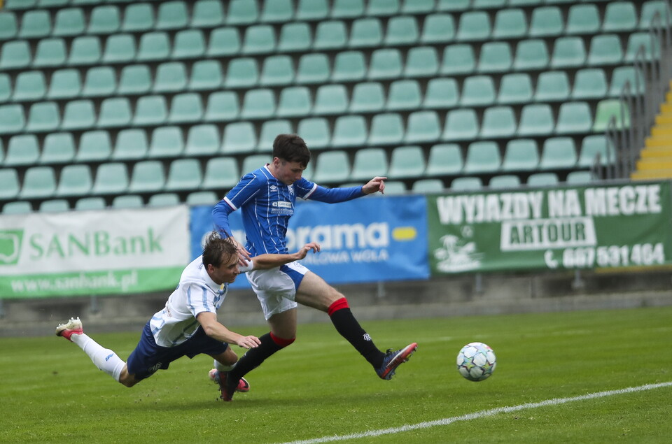Two players on a football field; one in white and blue, the other in white and blue.