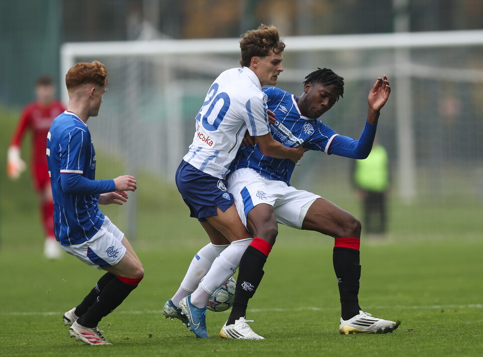 Players in blue and white jerseys engage in a football match, one holding the ball.