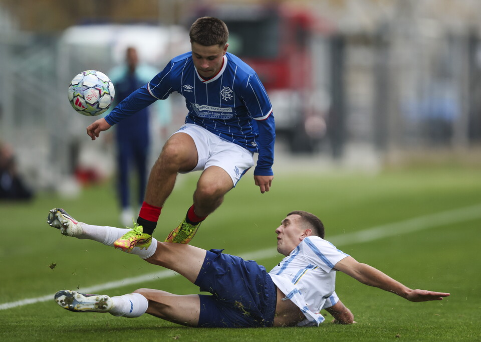 Two players in blue and white clash for a ball, one mid-air.