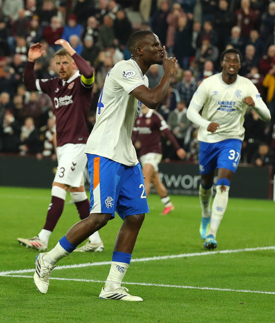 Footballers celebrate a goal with the number 3 player in blue shorts leading the way.