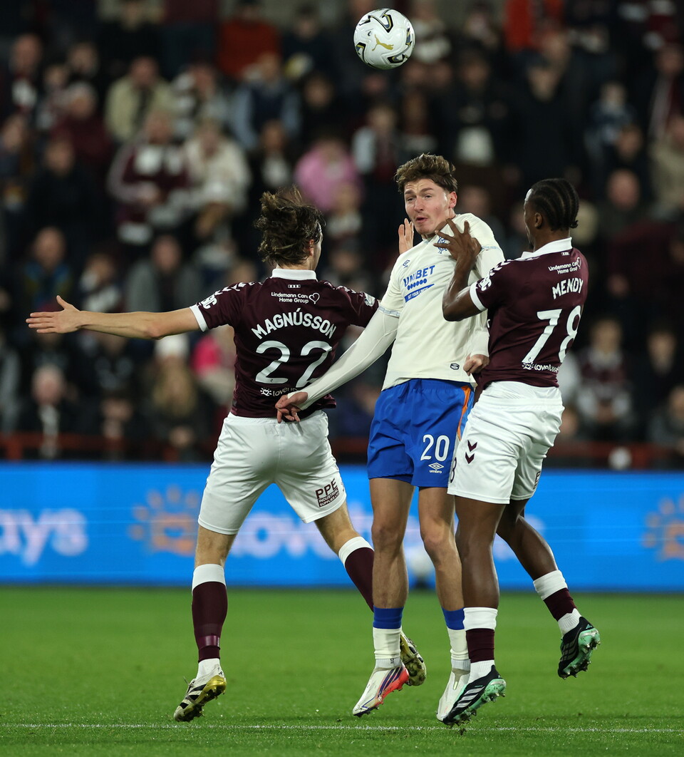 Three football players with shirts numbered 22, 20 and 78 jumping to hit a soccer ball.
