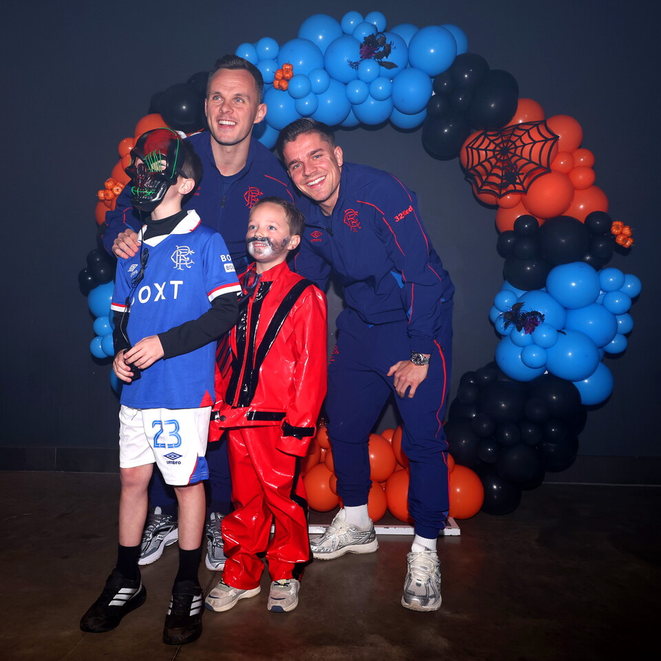 Three people posing in front of a balloon arch for a photo