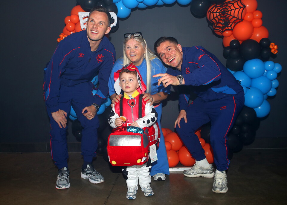 Four Manchester United players in blue outfits with a child in a fireman's outfit