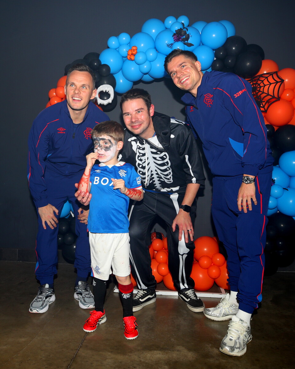 Four men and a young boy pose for a photo in front of a Halloween backdrop.