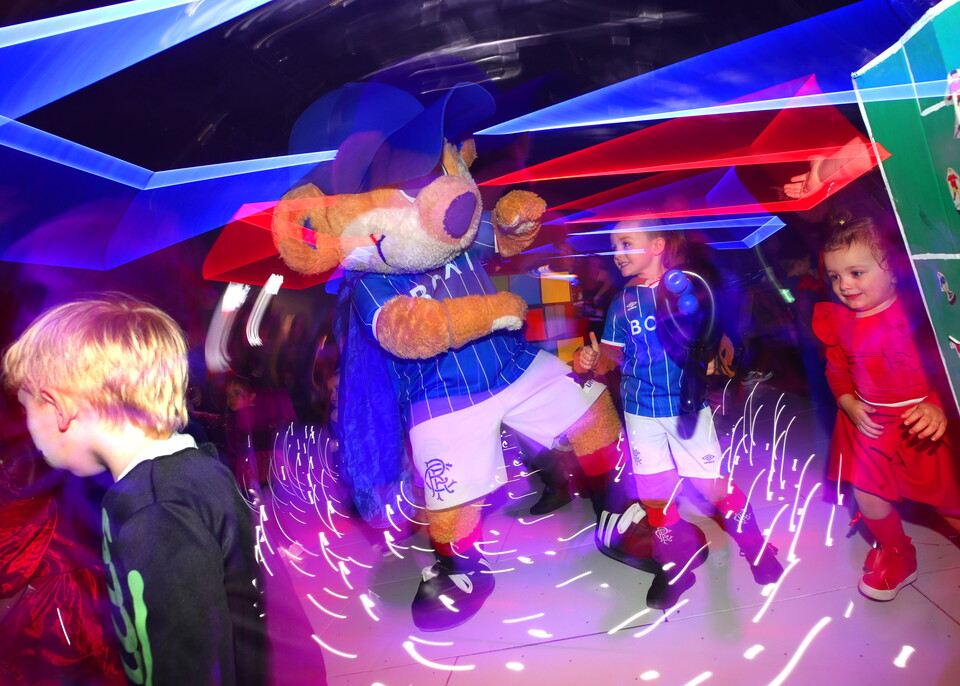 Mascot at football event with kids wearing blue and white kits