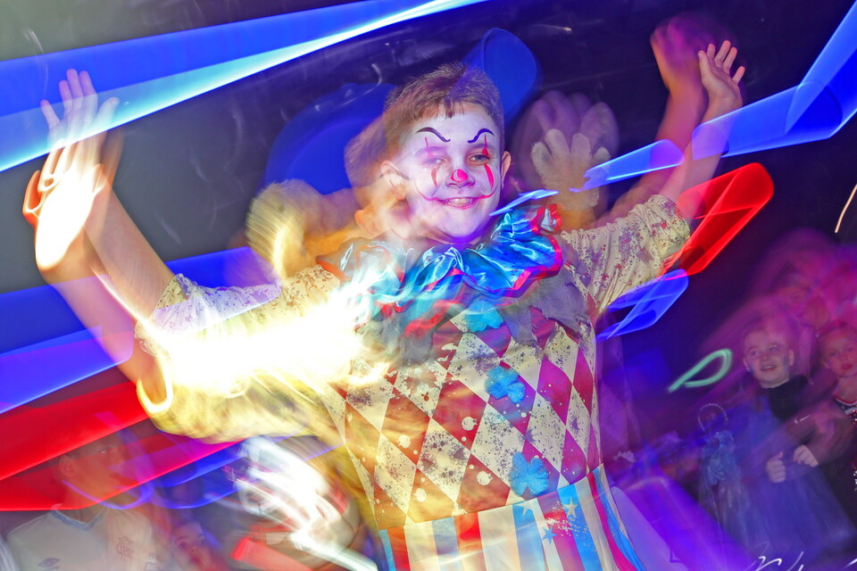 A clown at a club event with colourful lights and blurred background