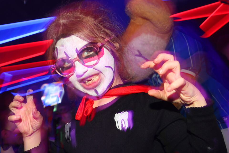 Woman with clown makeup holding a blue lollipop at a Halloween party