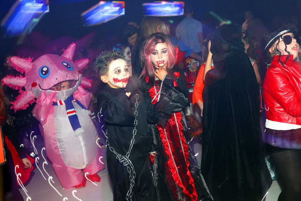 Three people wearing costumes at a party, one in a pink costume, one in black, and one in red.