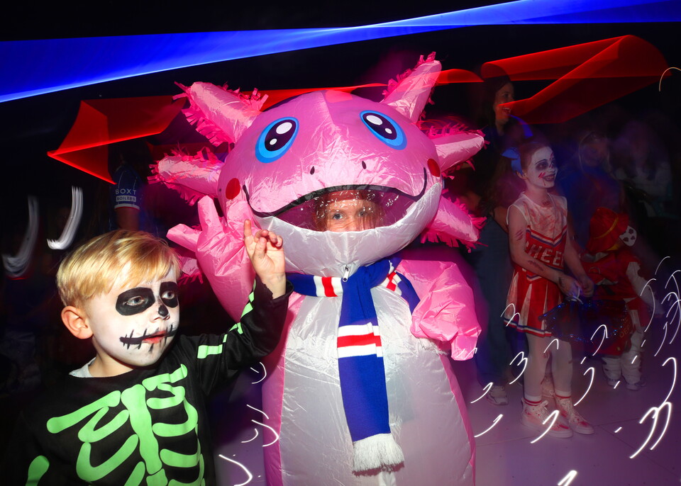 Child in skeleton costume holding pink balloon at Halloween party