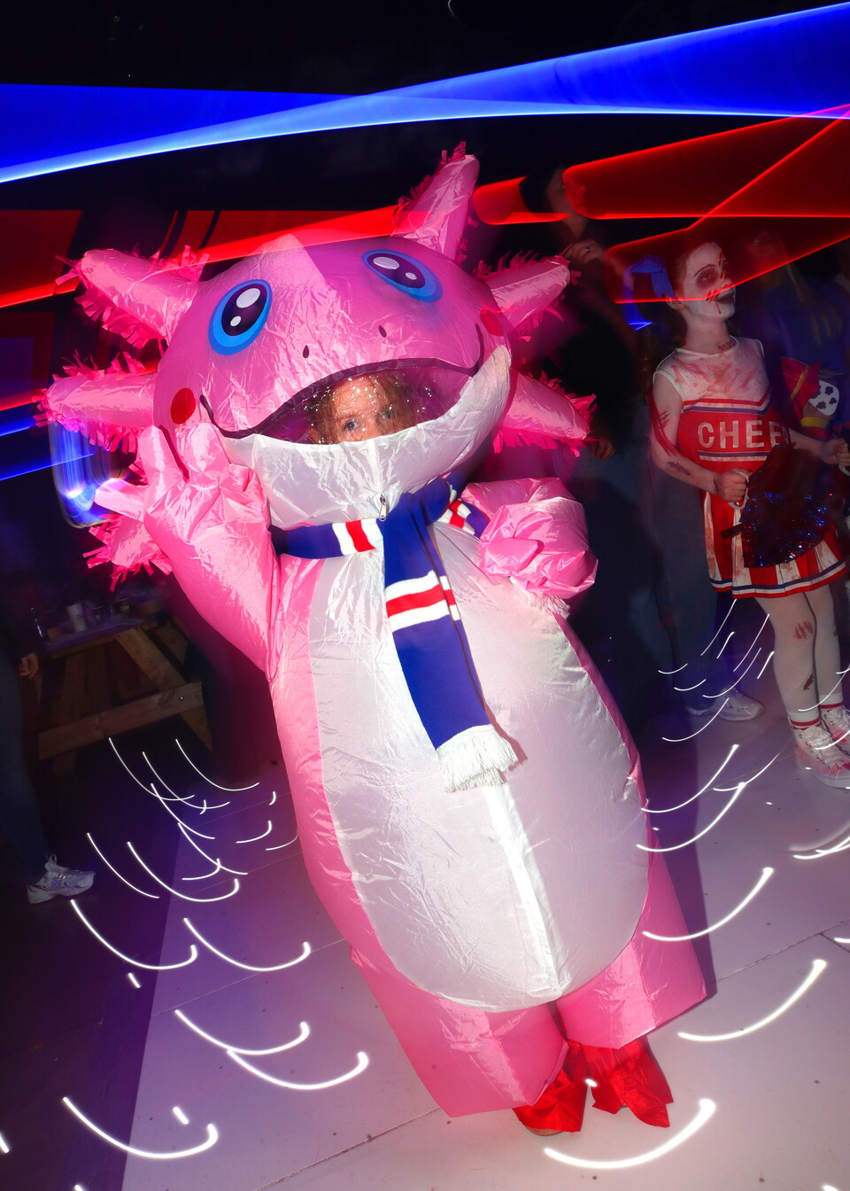 Child in a pink inflatable dragon costume with red boots at a party