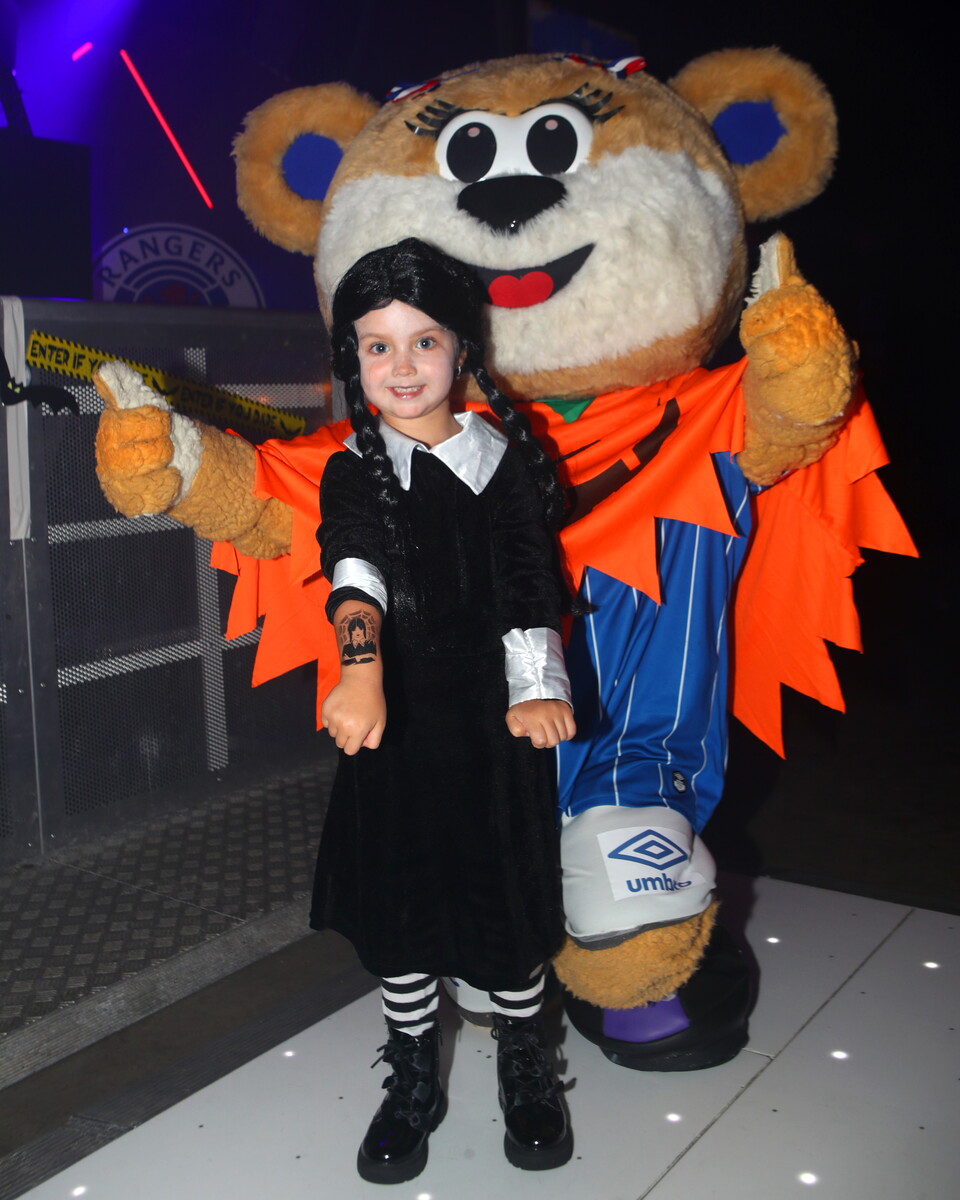 Child in Halloween costume next to mascot