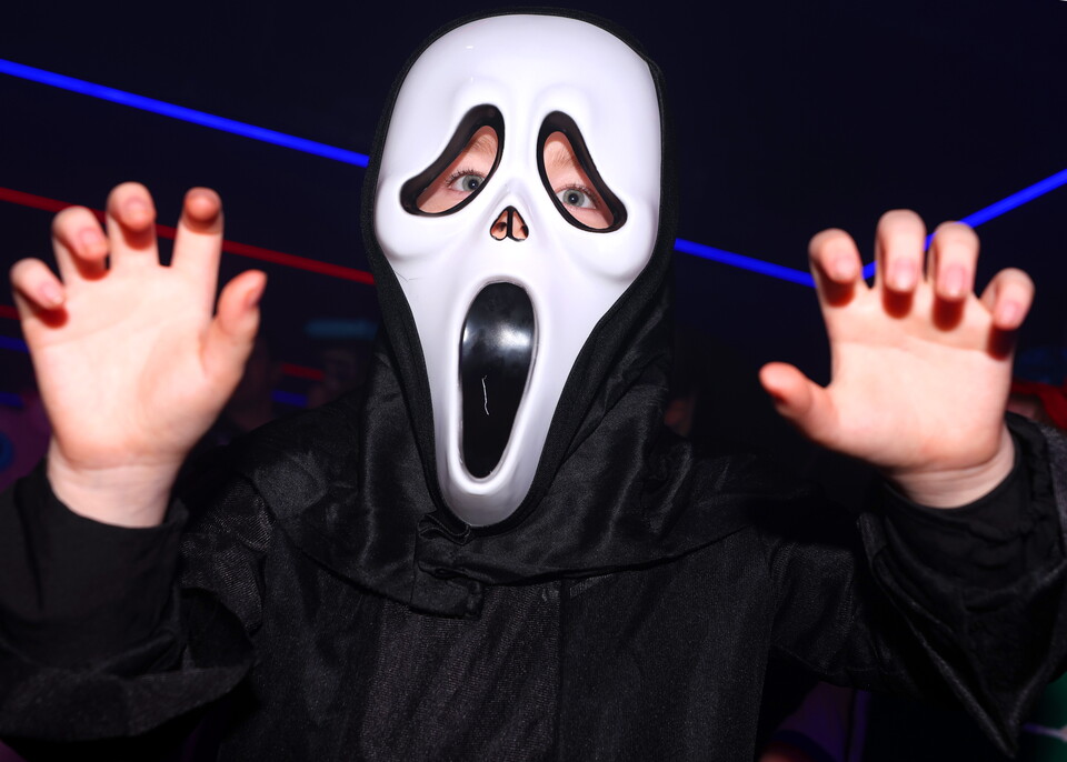 Person in a Ghostface mask from Scream at a party.