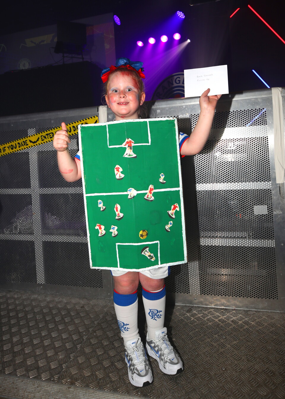 Child in a football costume giving a thumbs up