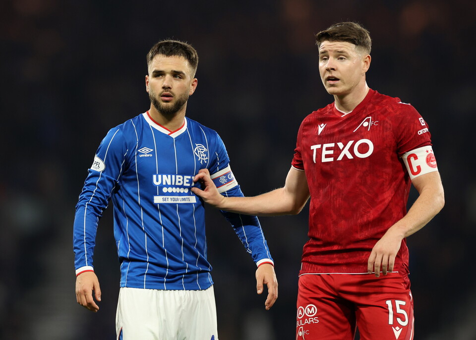 Two football players in different shirts; one in blue and white, another in red.