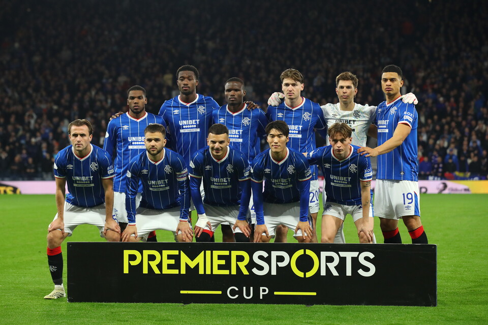 Football team in blue shirts posing for a photo in front of a Premier Sports Cup sign
