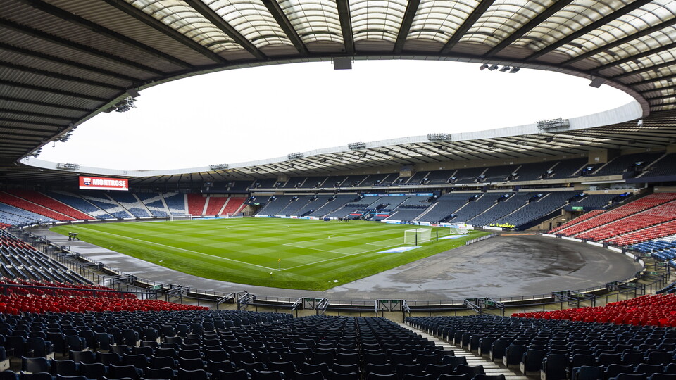 Empty stadium with red and blue seating and a green football field