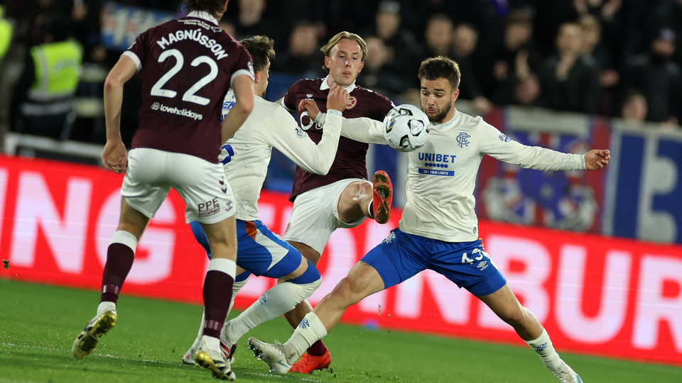 Three football players on a field. Two in maroon and white, one in blue and white.