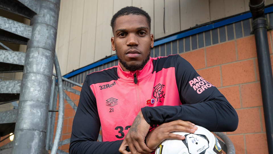 Football player wearing pink number 33 shirt holding a soccer ball.