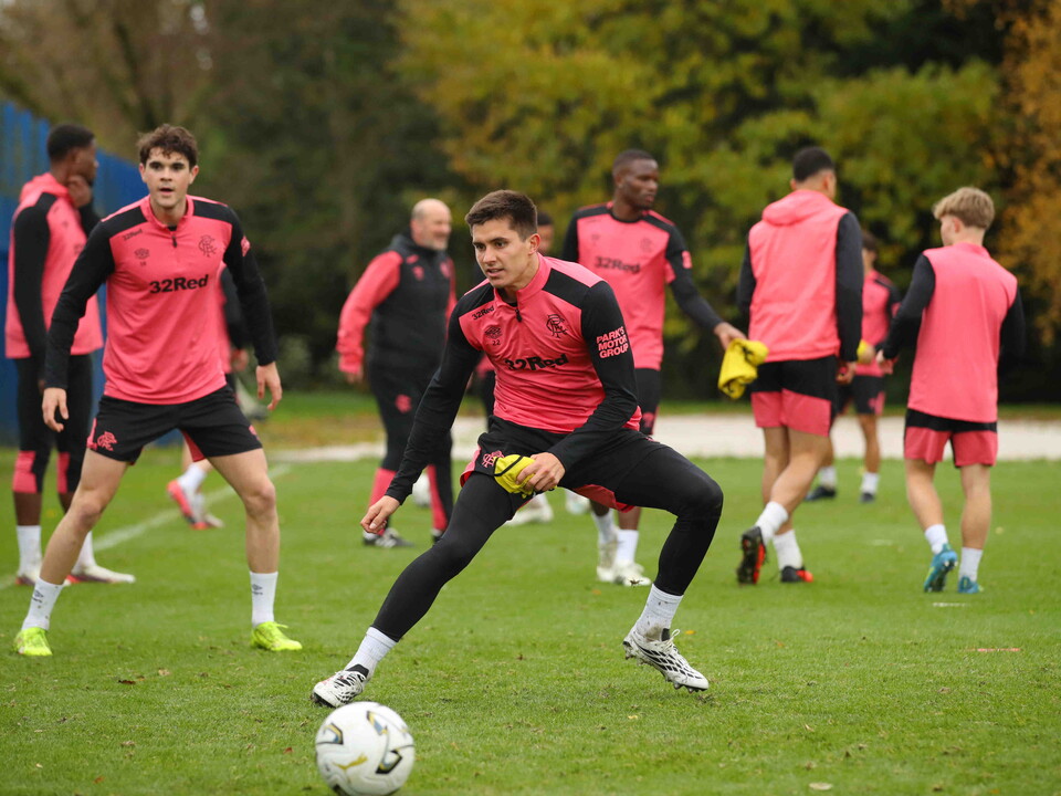 Soccer players wearing pink and black training suits on a field
