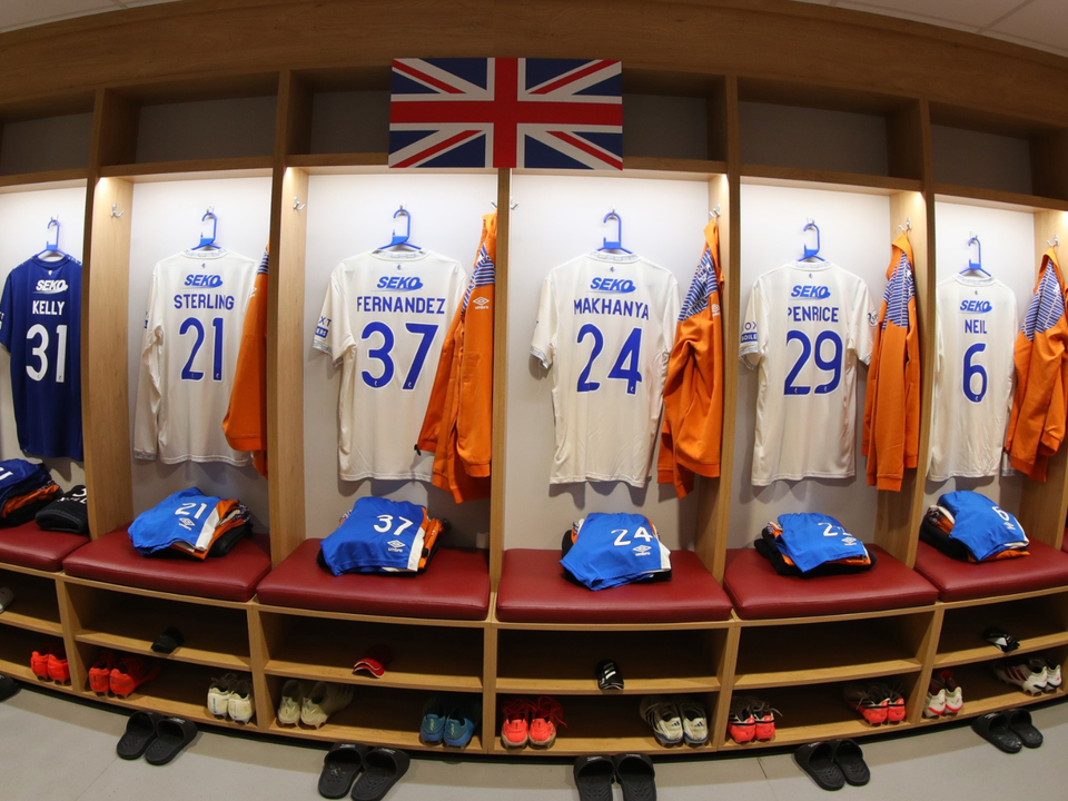 A locker room with numbered shirts hanging on a wall and a flag of the UK