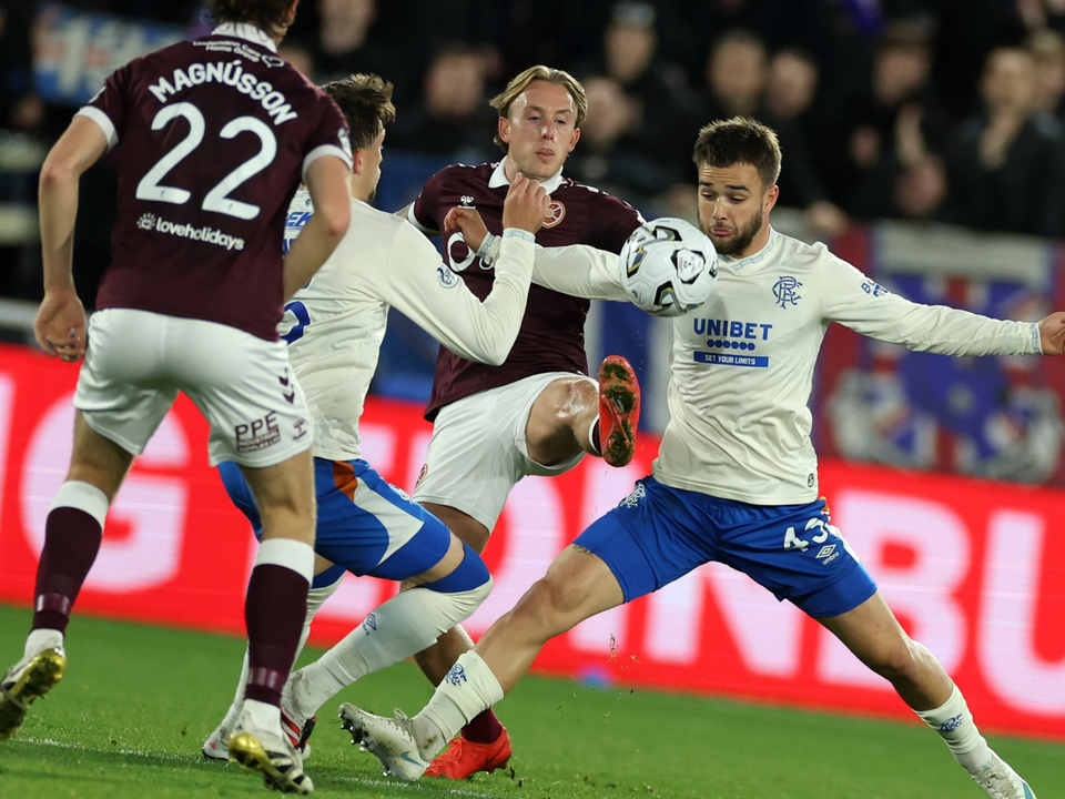 Three football players on a field. Two in maroon and white, one in blue and white.
