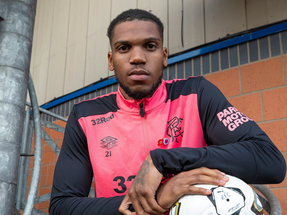 Football player wearing pink number 33 shirt holding a soccer ball.